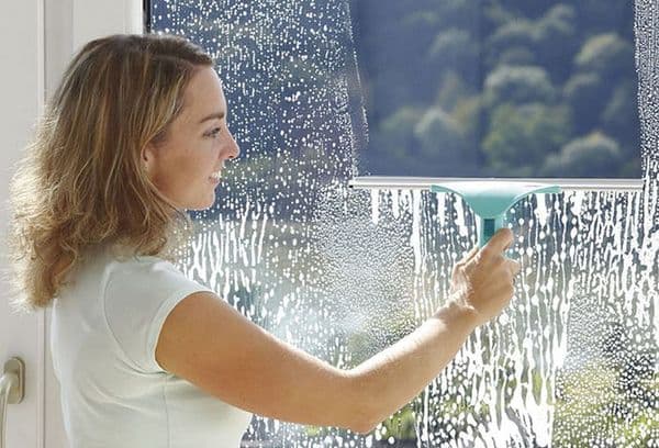 Frau putzt Fenster