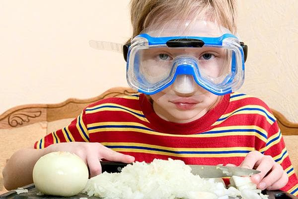 Ein Junge schneidet eine Zwiebel mit einer Schwimmbrille