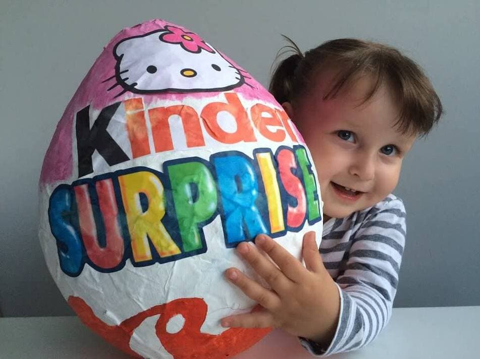 Kind mit einem riesigen Überraschungsei aus Pappmaché