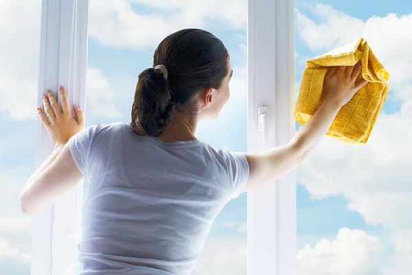 Frau putzt Fenster bei Sonnenschein