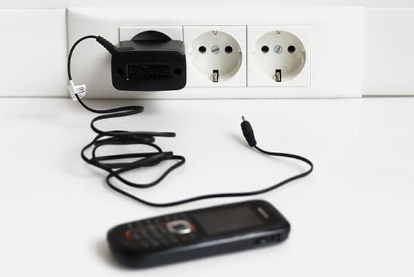 In der Steckdose gelassenes Telefonladegerät