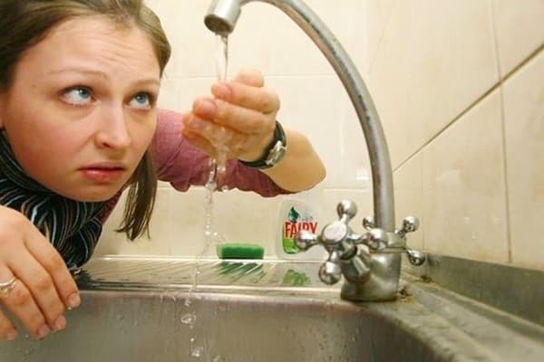 Eine Frau betrachtet das Wasser aus dem Wasserhahn