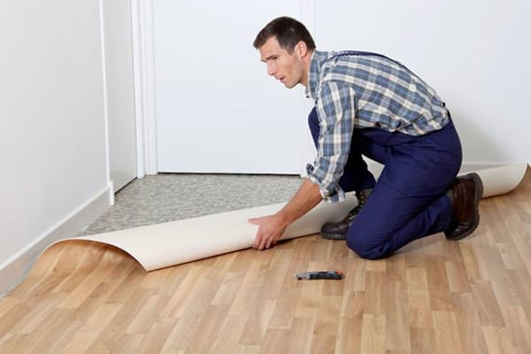 Ein Mann verlegt neues Linoleum auf altes