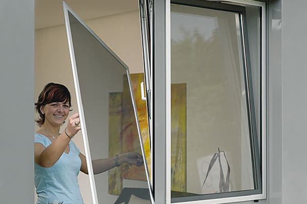 Frau entfernt das Netz vom Fenster