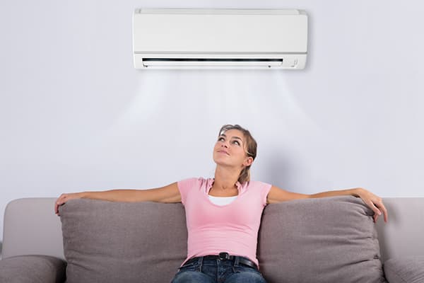 Eine Frau sitzt unter der Klimaanlage