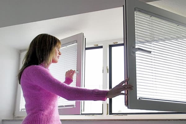 Frau öffnet das Fenster zum Lüften