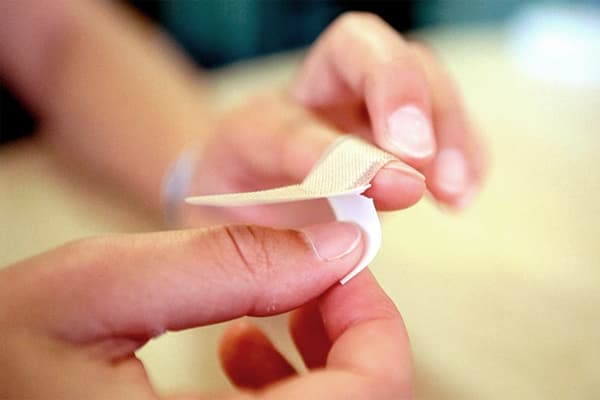 Eine Frau klebt ihren Finger mit einem Pflaster ab