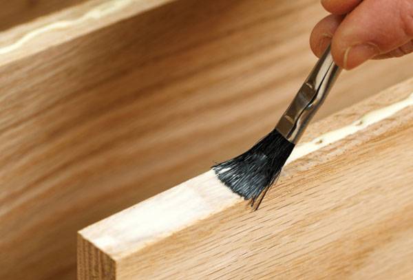 Auftragen des Klebstoffs auf ein Holzmöbelteil