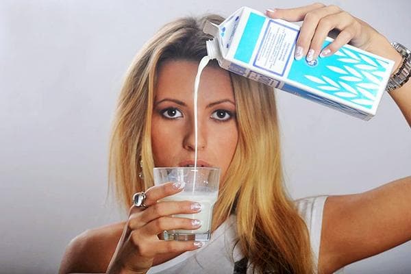 Eine junge Frau gießt Milch in ein Glas.