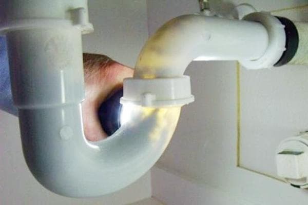 Überprüfung des Rohres unter dem Waschbecken im Gegenlicht