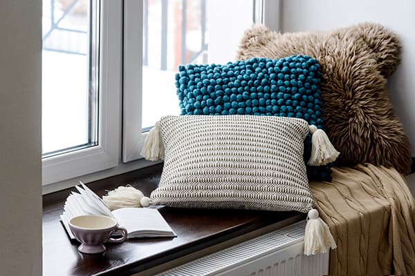 Kissen, Tasse und Buch auf der Fensterbank