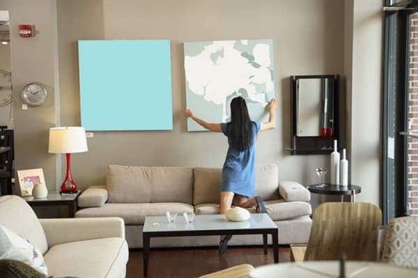 Die junge Frau nimmt das Bild von der Wand ab
