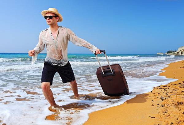 Mann am Strand mit Koffer
