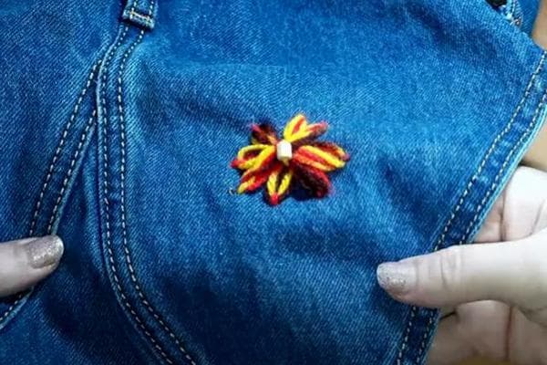 Eine Blume an der Stelle des Lochs in der Jeans