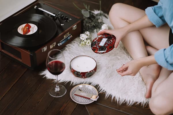 Eine junge Frau trinkt Wein am Grammophon