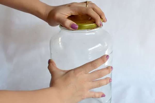 Eine Frau verschließt ein Glas mit einem Deckel.
