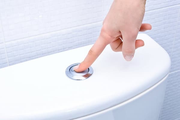 Drücken der Spültaste am Toilettenspülkasten