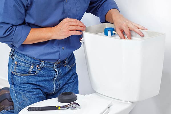 Ein Installateur repariert den Toilettenspülkasten