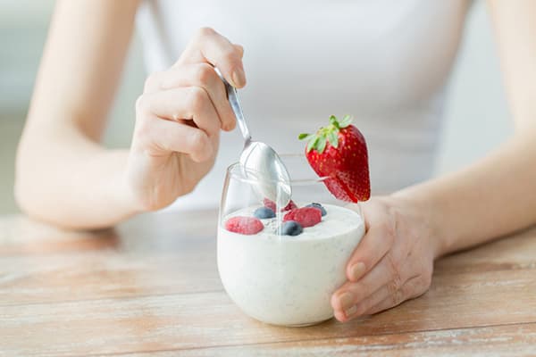 Eine junge Frau isst fettarmen Joghurt mit Beeren