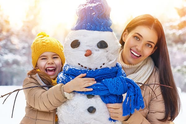 Mutter und Tochter bauen einen Schneemann