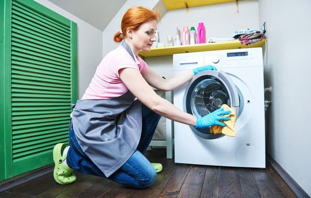 Frau reinigt die Waschmaschine