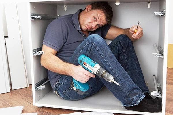 Ein Mann baut einen Küchenschrank zusammen