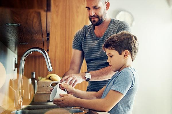 Vater bringt seinem Sohn das Geschirrspülen bei