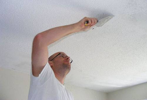 Entfernen der Kalkfarbe von der Decke mit einem Spachtel