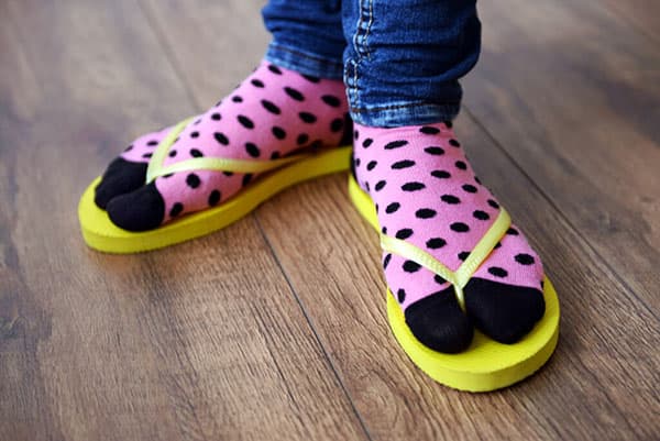 Füße in bunten Socken und Flip-Flops