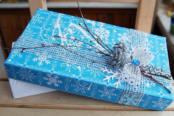 Dekoration einer Geschenkschachtel mit Spitze und Zweigen