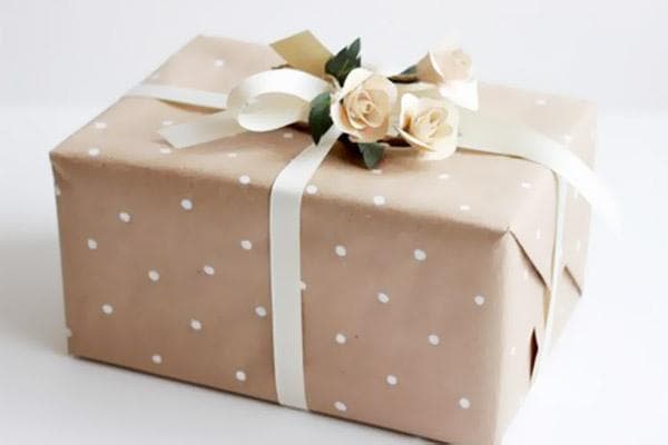 Ein Geschenk in Kraftpapier, verziert mit Bändern und Röschen