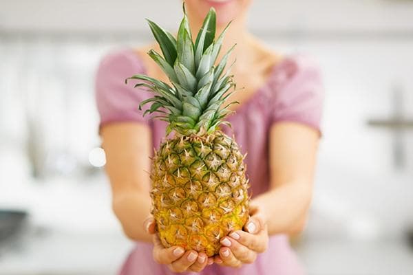 Eine Frau hält eine Ananas