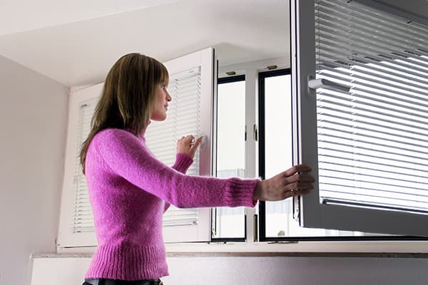 Frau öffnet das Fenster zum Lüften